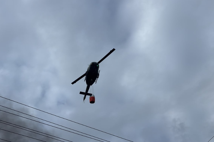 Helicóptero realiza descargas de agua para combatir incendio en L&R Comercial